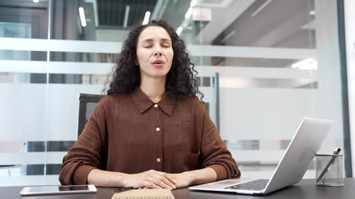 Smiling Woman Sits at Desk in Modern Office