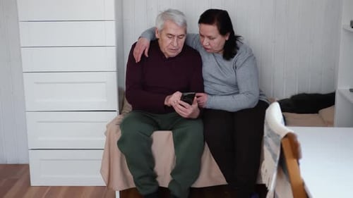 Loving Senior Couple Looking at Phone Indoors