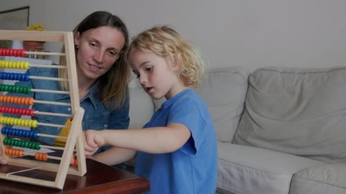 Home school education: Mother and child studying math for kindergarten homework with abacus