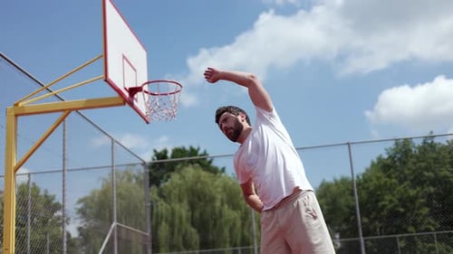 Athletic Man Stretching on Basketball Court Outdoors
