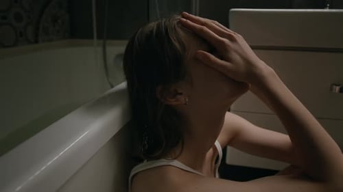 Close-up of Devastated Young Woman Covering Face with Hands Crying in Bathroom