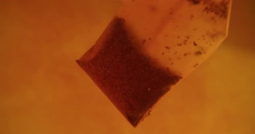 Close up of tea bag diffusing in a clear glass. Macro slow motion shot of the process of brewing