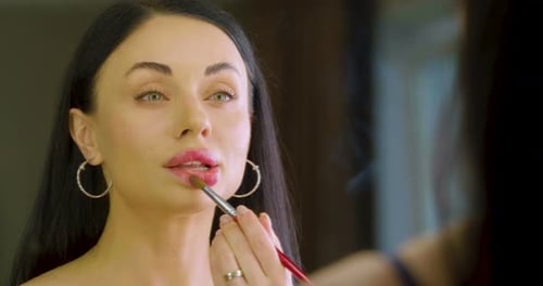 Elegant Woman Applying Lipstick with Brush