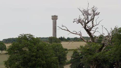 Drone aerial view of a rural water tower rising above countryside fields