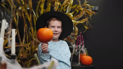 Boy Dressed as a Witch Holds a Pumpkin