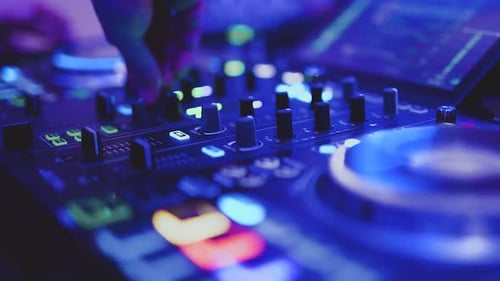 DJ mixando música à mão em uma festa em uma mesa de mixagem colorida, de perto