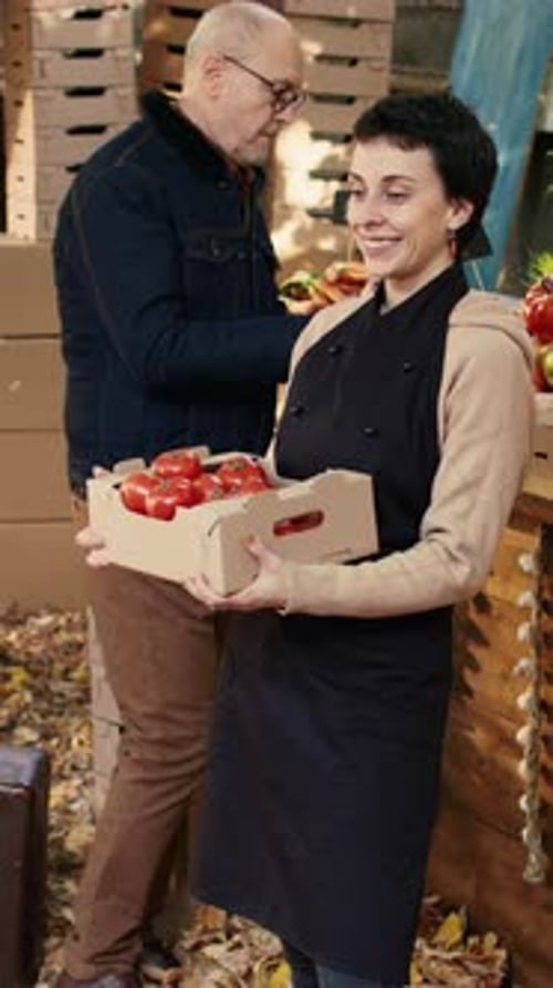 Woman Smiling Holding Tomatoes at Outdoor Market