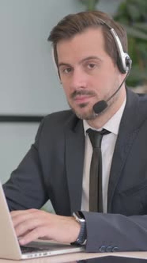 Businessman with Headset Looking toward Camera in Call Center, vertical video