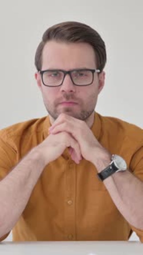 Contemplative Man with Glasses Sitting at a Desk