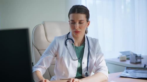 Focused Doctor Typing Keyboard Analyzing Scan Looking Xray in Medical Office