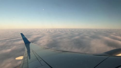 Airplane Flying Above the Clouds Making a Turn. Window View From Inside of the Plane.
