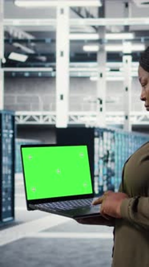 Woman Using Laptop with Green Screen in Datacenter