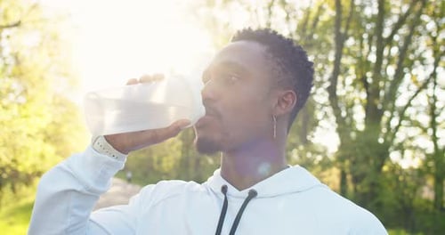 Close Up Portrait of Handsome African American Young Male Standing Outdoors Drinking Water After