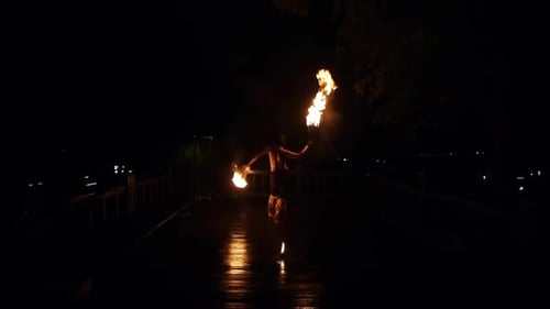 Fire Artist Twirling Flaming Batons at Night