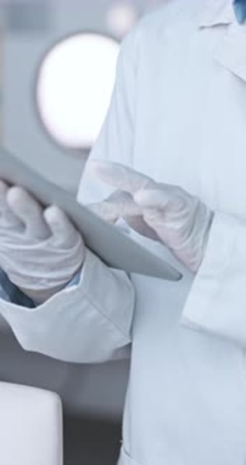 Person in Lab Coat Using Tablet Device