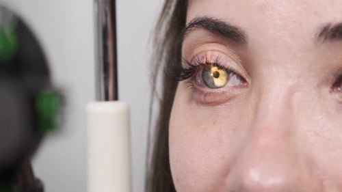 Attentive optometrist examining beautiful female patient with slit lamp in ophthalmology clinic. Opt