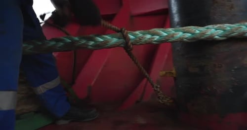 Arbeiter in Uniform wickelt Kabel auf dem Schiffsdeck auf ein Seil