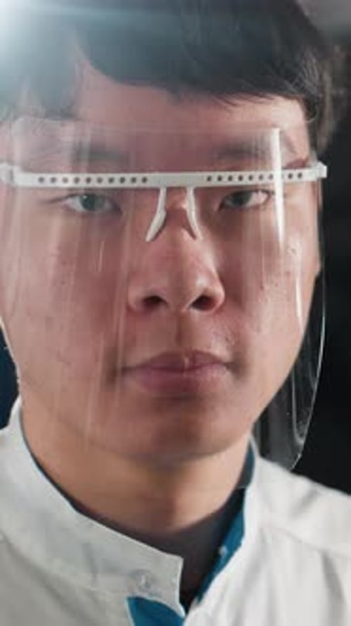 CloseUp of Chinese Student Adjusting Protective Glass in Illuminated Workshop