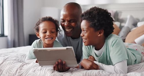 Dad and Sons Enjoying Tablet on Bed Together