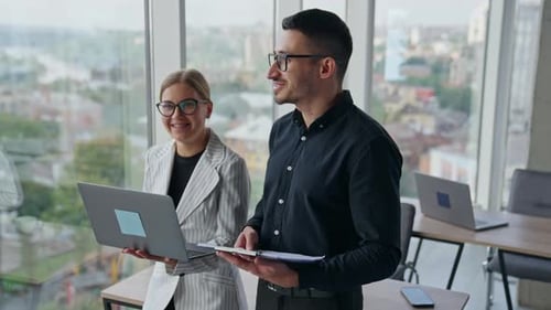 Friendly talking colleagues standing at the desk in office.