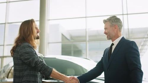 Buyer of Car Shaking Hands with Seller in Auto Dealership Closeup of Handshake