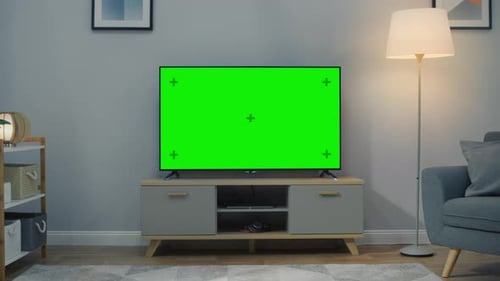 Zoom Out Shot of a TV with Horizontal Green Screen Mock Up. Cozy Living Room at Day Time with a Cha