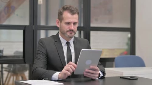 Businessman Works on Tablet in Modern Office