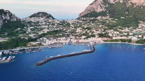 Vibrant Coastal Harbor of Capri Nestled Between Majestic Cliffs at Sunset Showcasing Boats and