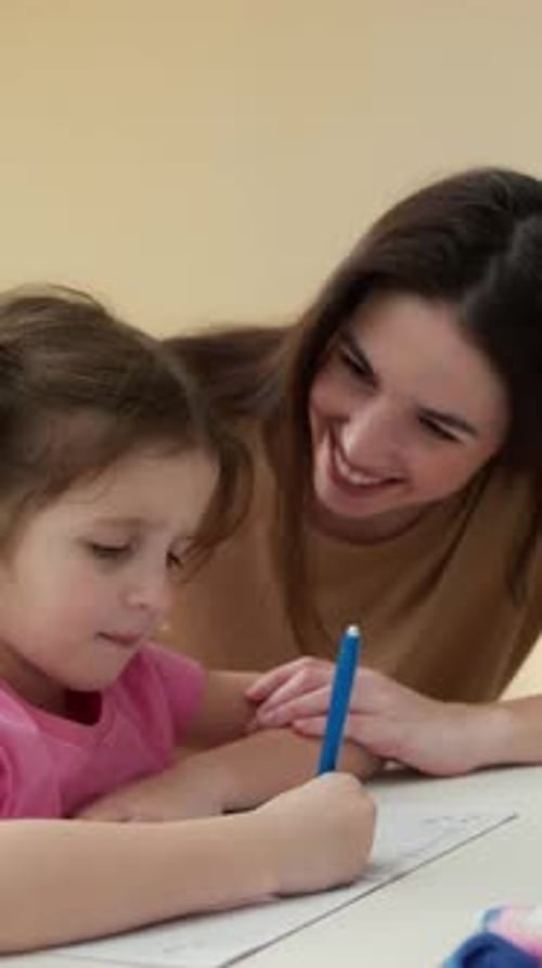 Child Draws with Woman Helping