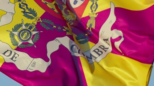 Super close-up of Coimbra's colorful flag waving in the wind against a bright blue sky