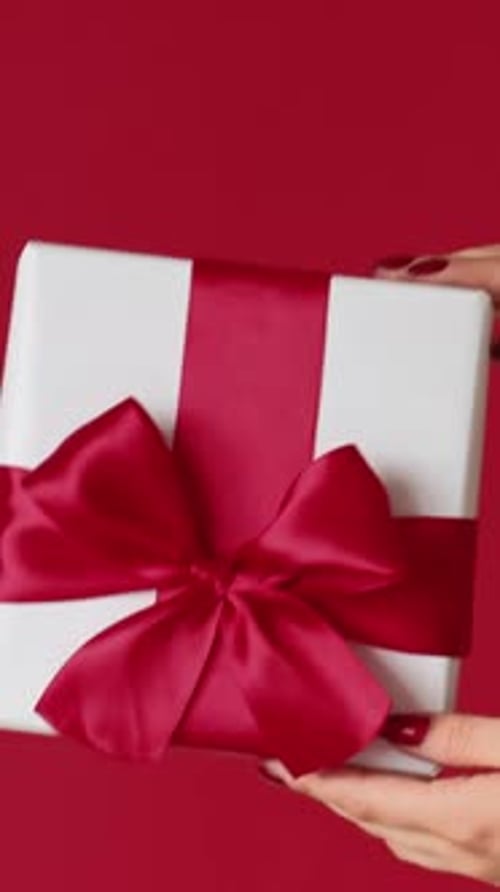 Hands Holding White Gift Box with Red Bow