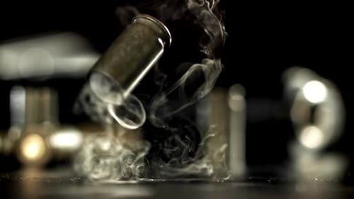 Bullet casing falls amid puffs of smoke close-up