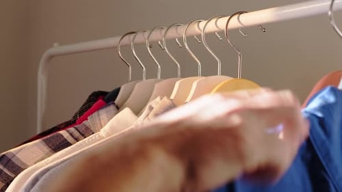 Hand Browsing Clothes on Hangers in Closet