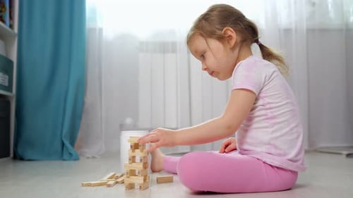 Kleines Mädchen baut zu Hause einen Holzblockturm
