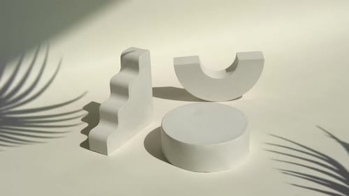 Minimalist White Geometric Pedestals with Moving Palm Shadows