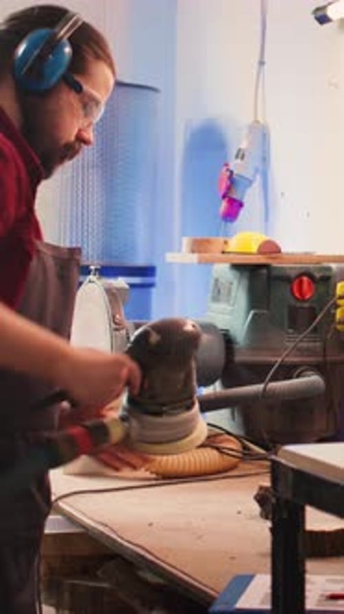 Vertical Video Artisan with Protecting Equipment Uses Angle Grinder on Wood