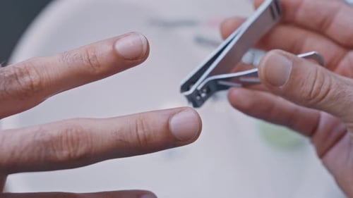 Man Trims His Nails With Clippers in Bathroom