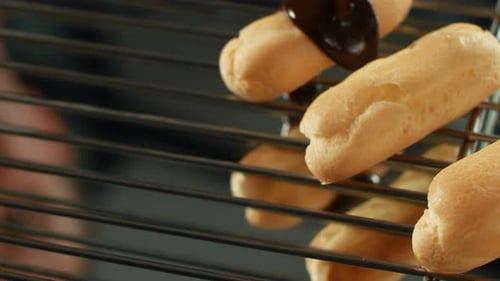 Pouring rich chocolate glaze over delicious eclair pastries