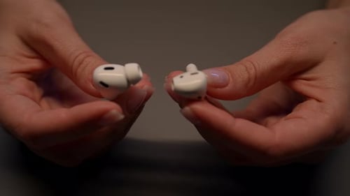 Woman Removing Earpieces From White Wireless Earbuds