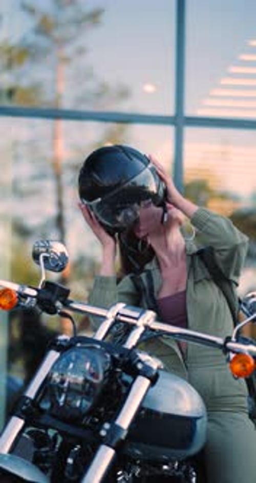 Woman removes motorcycle helmet outdoors on city street