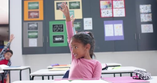In school, girl raising hand in classroom, participating in lesson