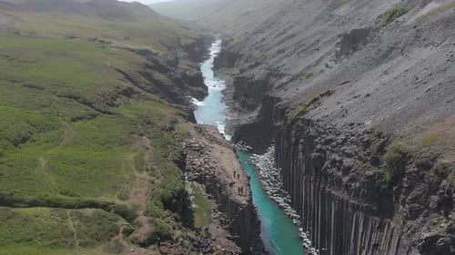 Famous tourist destination Stuðlagil with bright sunlight, turquoise glacial water, aerial