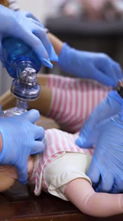 Medical Personnel Perform CPR on Infant Doll