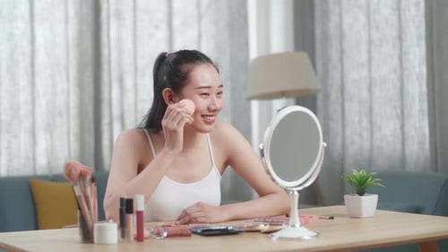 Beautiful Young Asian Woman Looks In The Mirror Applying Powder Face For Wellness Skin Care