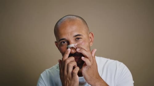 Adult Adjusts Bandage on Nose in Close Up Shot