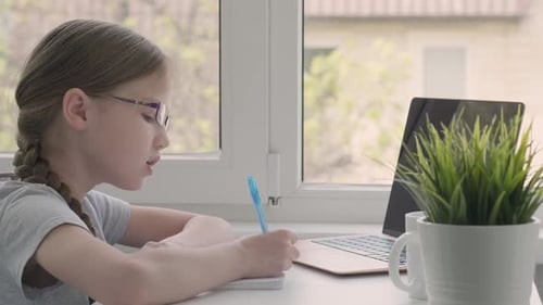 Young Girl Writing in Notebook While Studying