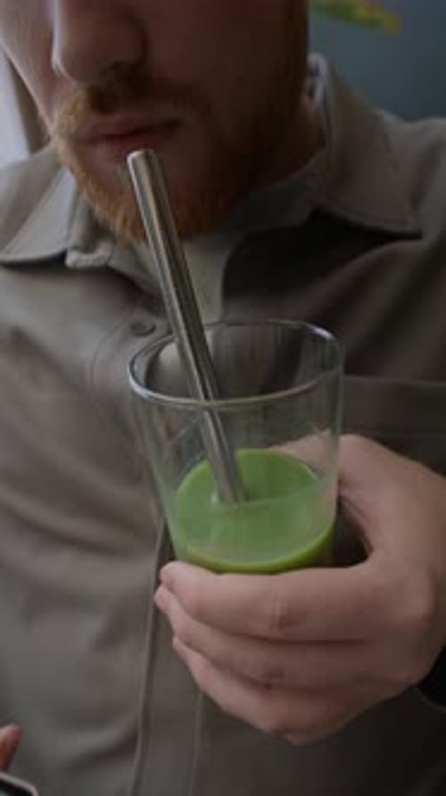 Young Adult Sipping Green Drink with Metal Straw