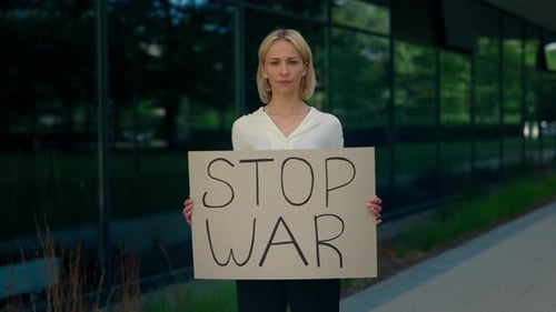 Kaukasische Frau hält Plakatkarton mit Stop-Kriegs-Botschaft in der Hand, Ukrainerin zeigt Stop-Kriegs-Poster