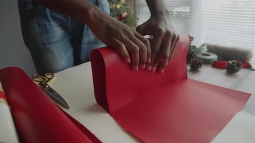 Person wrapping a Christmas gift at a table