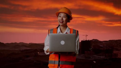 Asiatische Ingenieurin arbeitet auf der Baustelle an einem Laptop